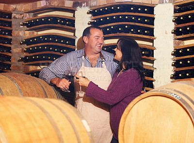 Buy stock photo Wine, oak barrels and a couple in a cellar for the storage, production or fermentation of alcohol at a winery. Love, manufacturing or industry with a mature man and woman drinking a beverage together