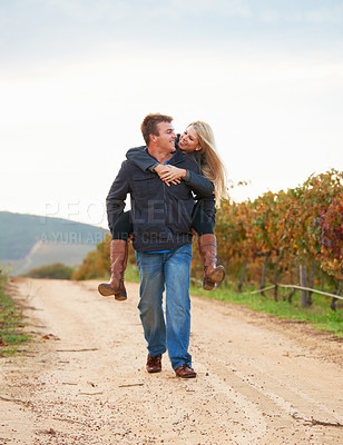 Buy stock photo A young man carrying his girlfriend on his back while taking a walk on a vineyard
