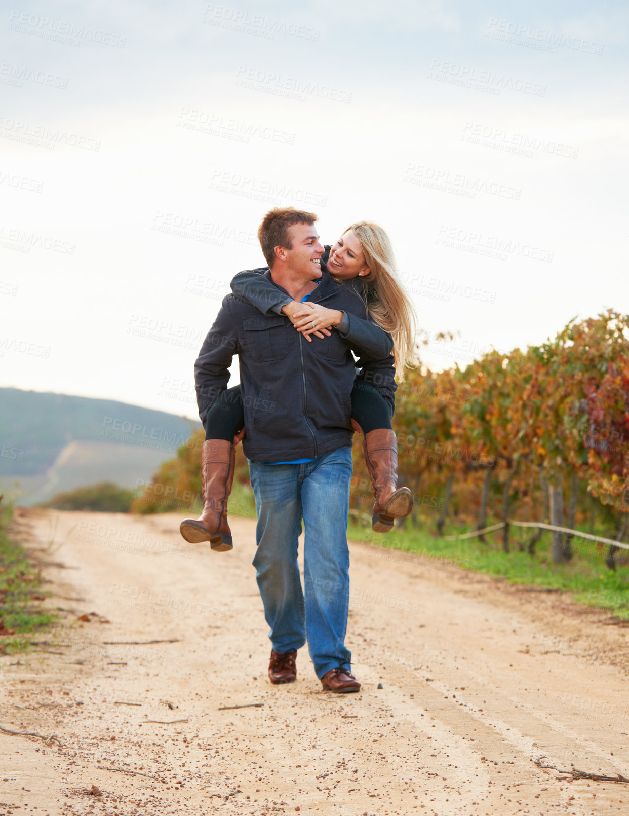 Buy stock photo A young man carrying his girlfriend on his back while taking a walk on a vineyard
