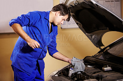 Buy stock photo Mechanic, oil and service with a man in a workshop to fix or repair a vehicle during routine maintenance. Engineer, inspection and labor with a young person working in a garage for car assessment