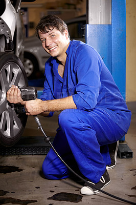 Buy stock photo Mechanic, man and smile by wheel in shop, electric drill and car service or repairs for maintenance. Technician, male person and tire change for automobile, rim and vehicle inspection in portrait
