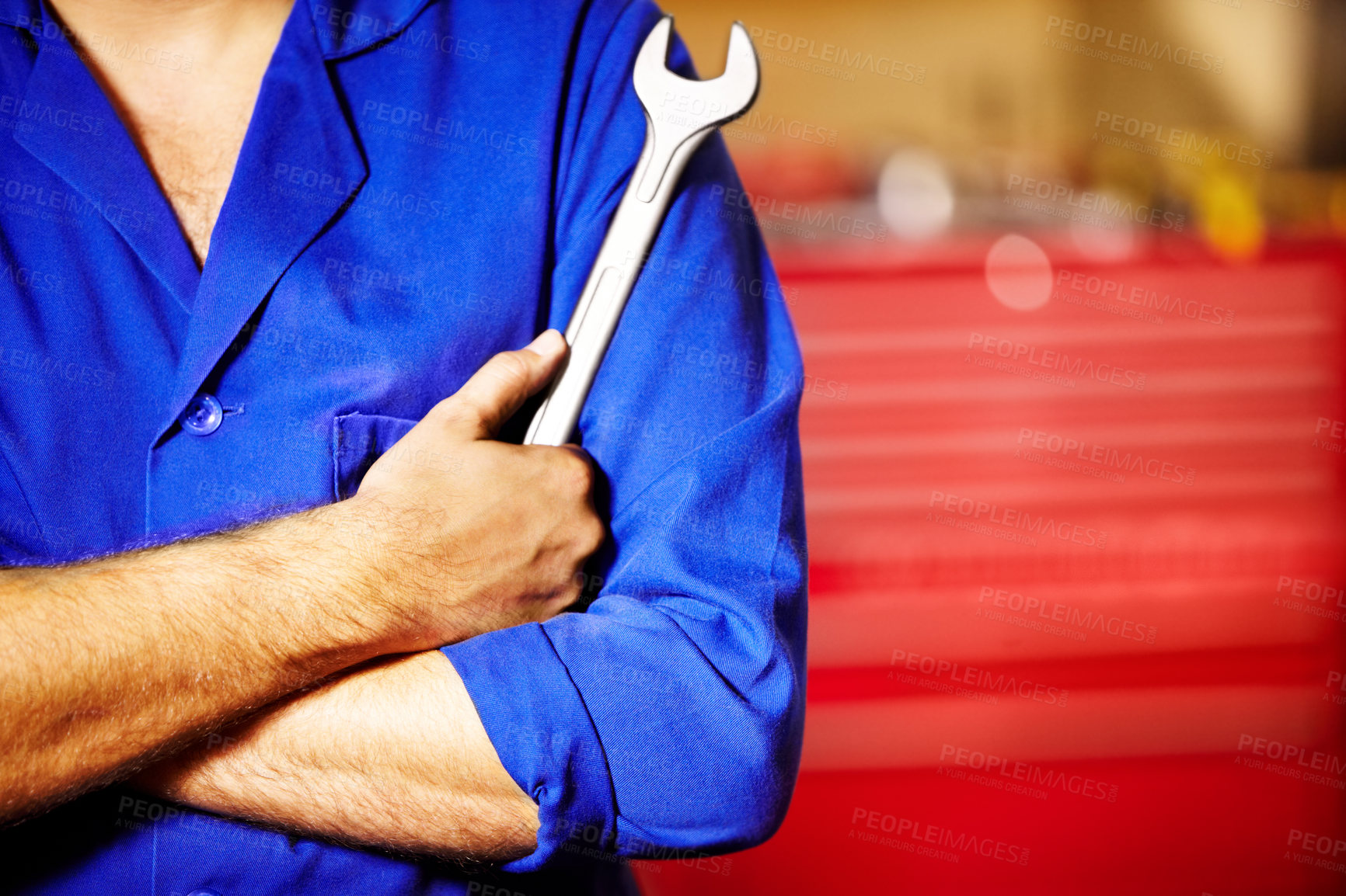 Buy stock photo Closeup male mechanic holding a spanner with his arms folded in a repair workshop. Tool in the hand of a man working on cars and performing services in a garage. For all your car care needs