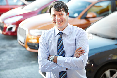Buy stock photo A man smiling confidently while standing in the lot of his dealership
