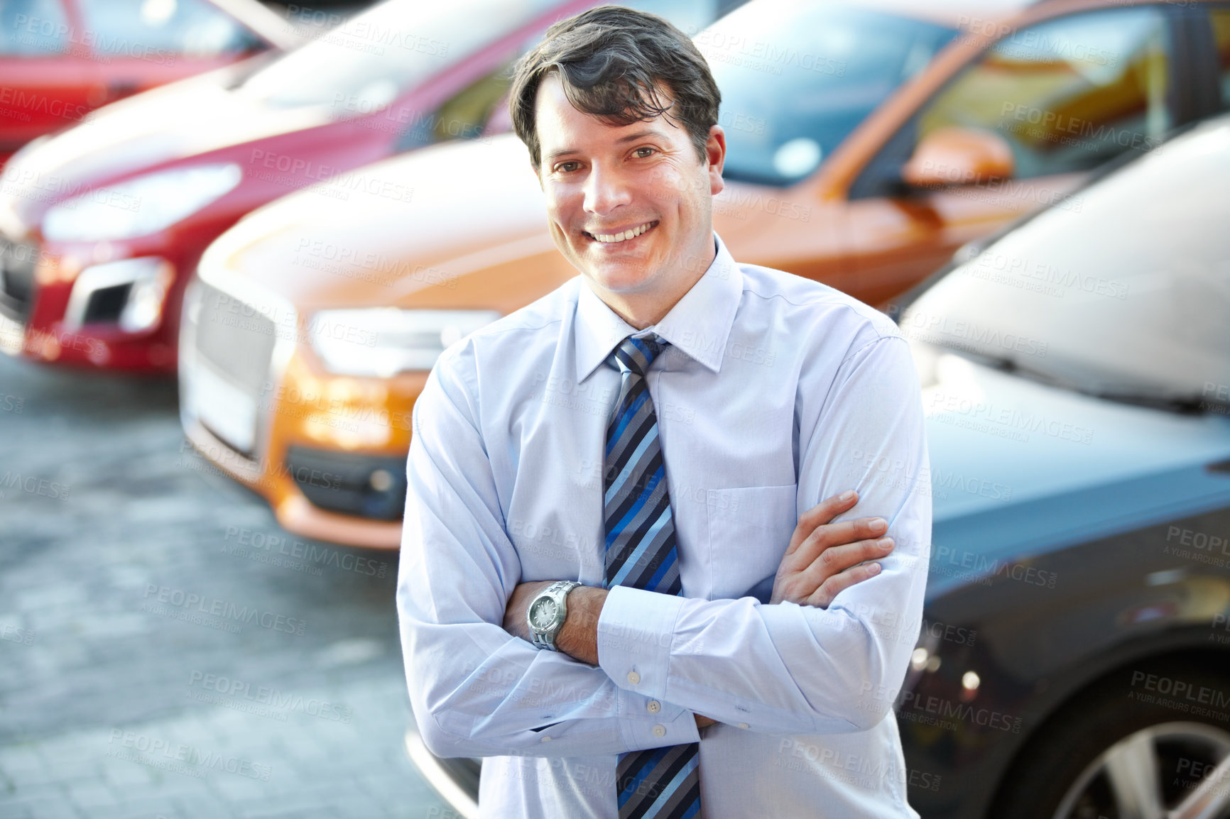 Buy stock photo A man smiling confidently while standing in the lot of his dealership