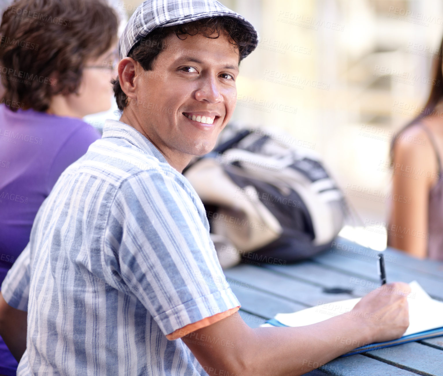 Buy stock photo A young ethnic man writing down some notes during break