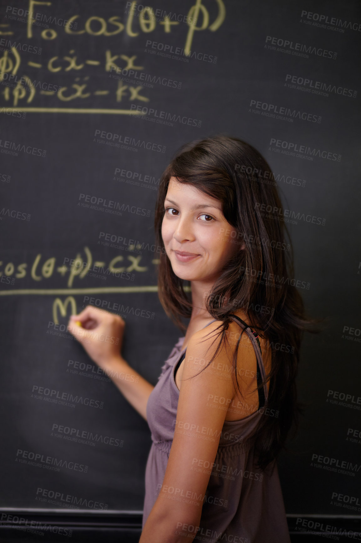Buy stock photo A young attractive Indian woman, solving a maths problem on the blackboard in class
