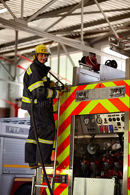 Buy stock photo A young male firefighter on the ladder at the back of a firetruck