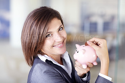 Buy stock photo Portrait of an attractive businesswoman putting a coin into a piggybank