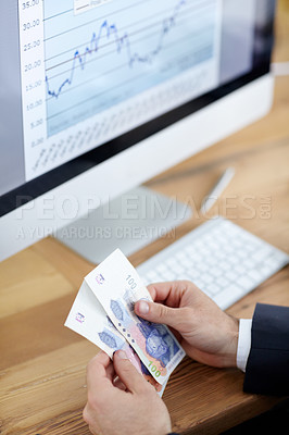 Buy stock photo Cropped shot of a businessman counting money in front of a computer