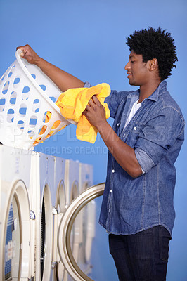 Buy stock photo A handsome man doing the laundry at the laundromat