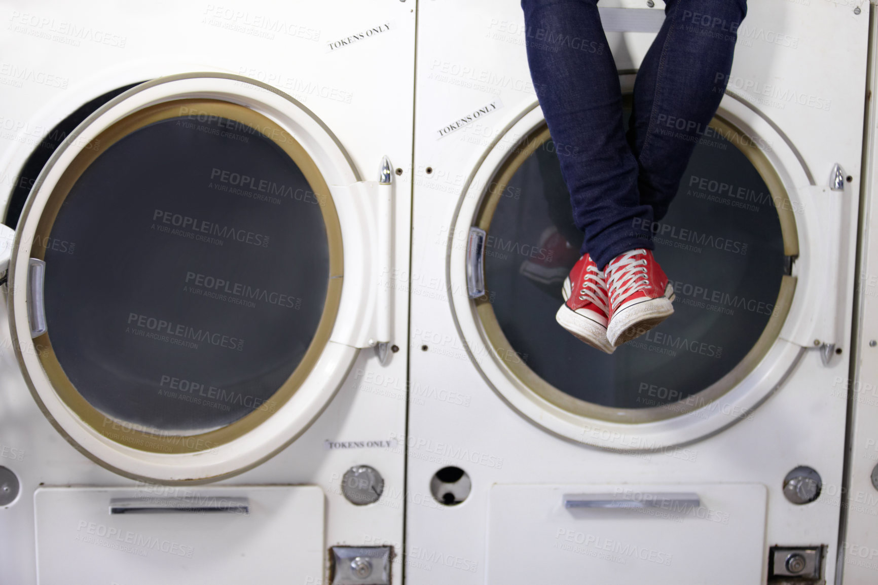 Buy stock photo Cropped image a man's legs as he sits on a washing machine at the laundromat