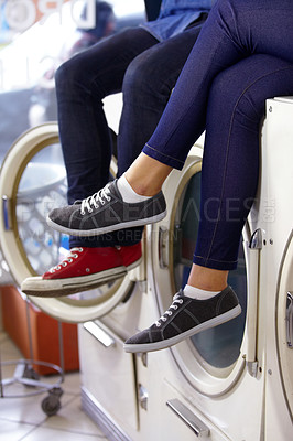 Buy stock photo Cropped image of a couple's legs and feet as they sit on a washing machine at the laundry