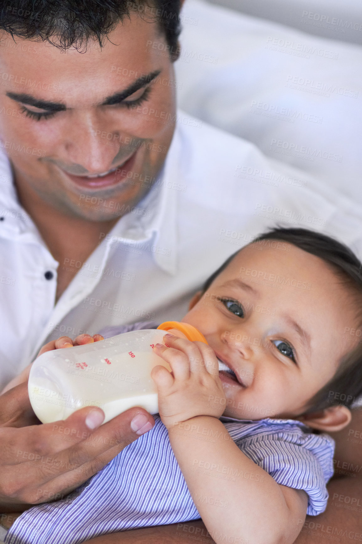 Buy stock photo A father feeding his baby boy a bottle of milk while sitting on the sofa
