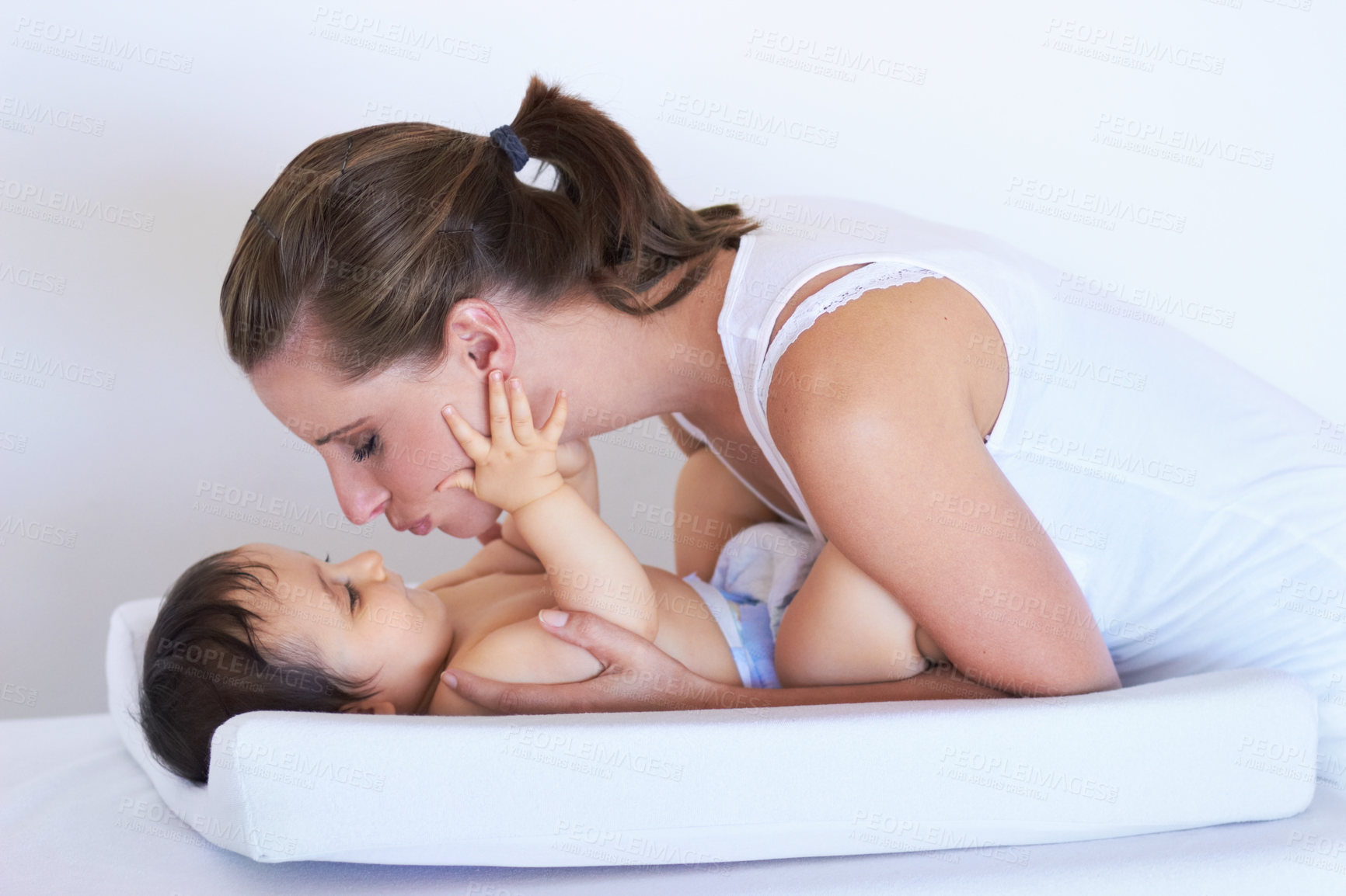 Buy stock photo Mother, smile and baby kiss at home on diaper changing table with happiness. Family, house and young child with mom feeling love, care and parent support from bonding together with cute kid and mama