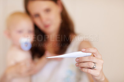 Buy stock photo A young mother holding her toddler boy while looking at a thermometer