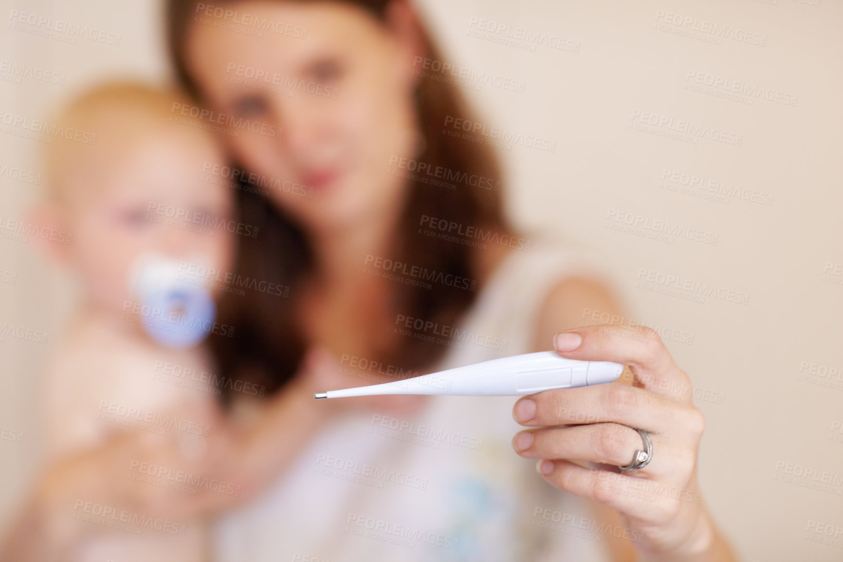 Buy stock photo A young mother holding her toddler boy while looking at a thermometer