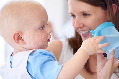 Buy stock photo Playing, happy and a mother with a baby and water, bonding and care with a drink in a house. Smile, family and a mom holding a baby with a bottle for play, quality time or happiness together