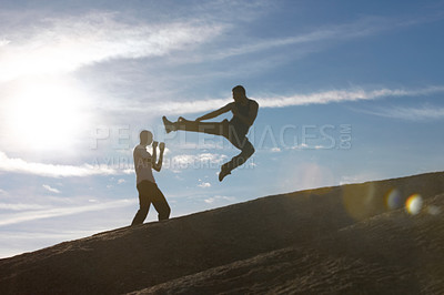 Buy stock photo Jump, kick and karate men on mountain top for fitness, training or body, speed or power on blue sky background. Martial arts, taekwondo or MMA friends workout in nature for cardio, exercise or sports