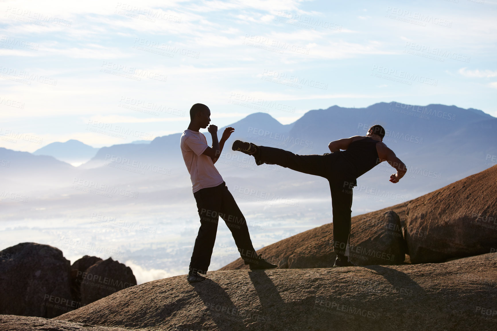 Buy stock photo Two male kickboxers training on a mountain top