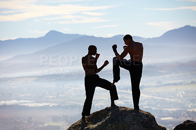 Buy stock photo A male kickboxer practising their technique on a mountain peak