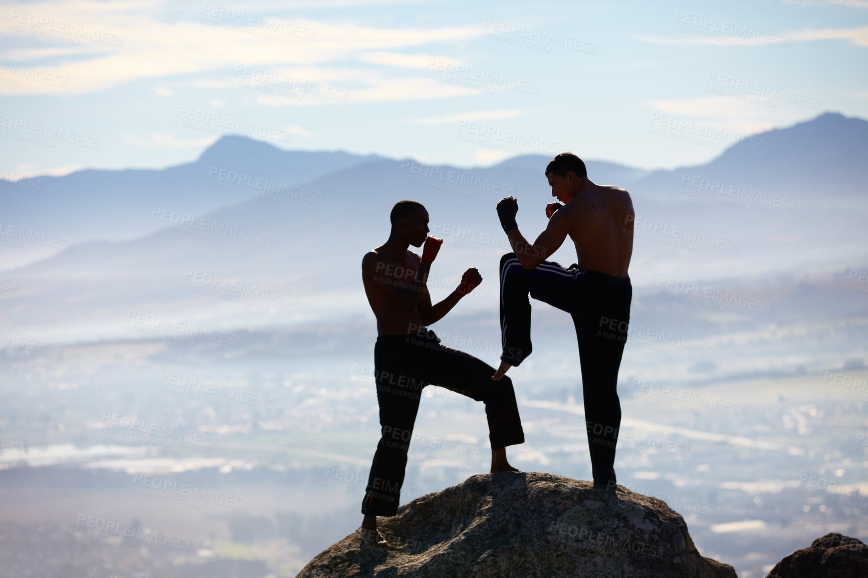 Buy stock photo A male kickboxer practising their technique on a mountain peak