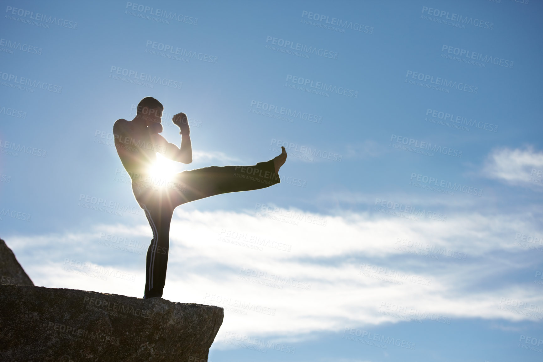 Buy stock photo Fitness, kick and karate man on mountain top for body, power or defense training on blue sky background. Martial arts, MMA and male taekwondo master in nature for exercise, sports or morning cardio