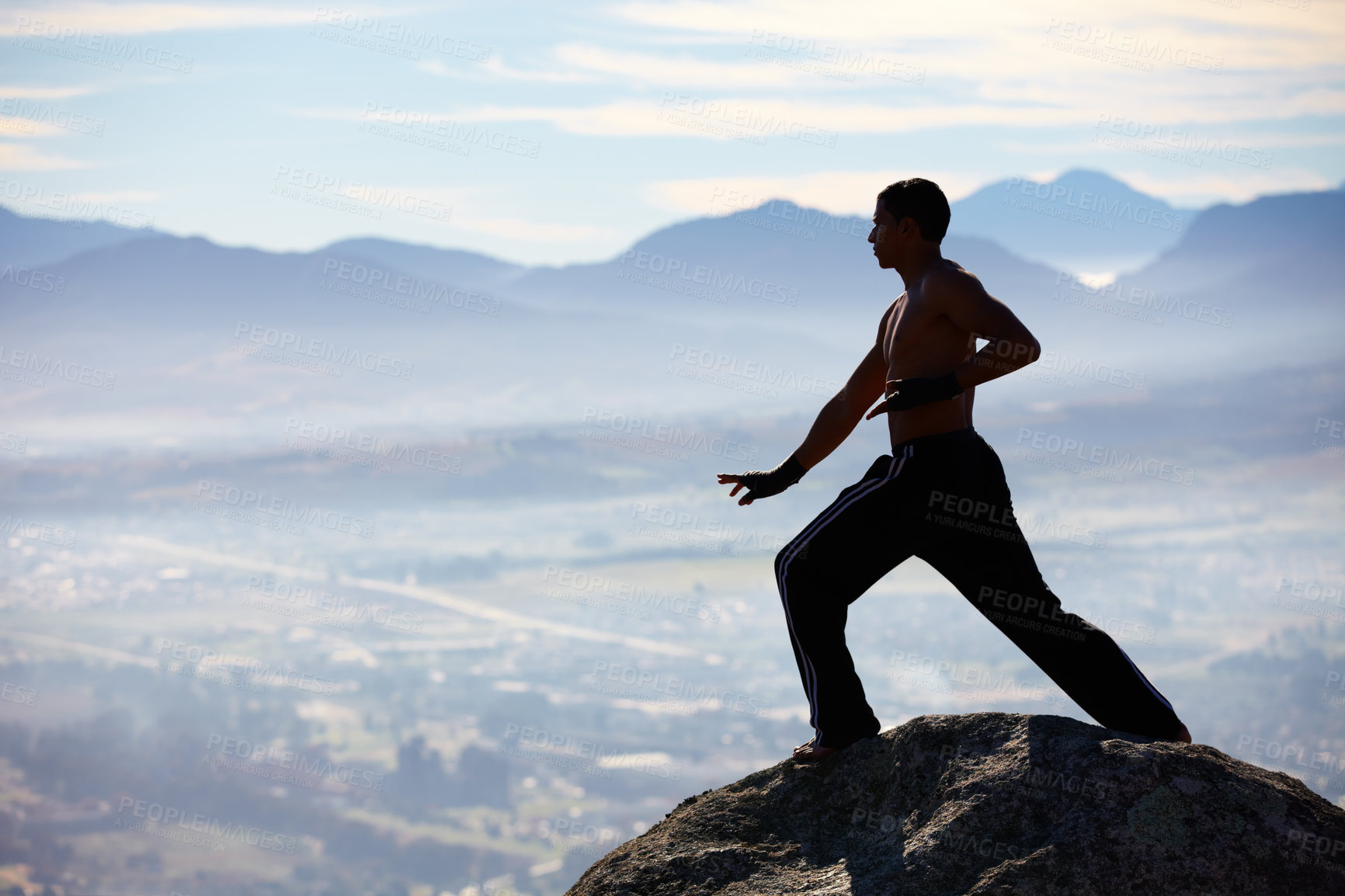 Buy stock photo A male kickboxer high up on a mountain top to practice