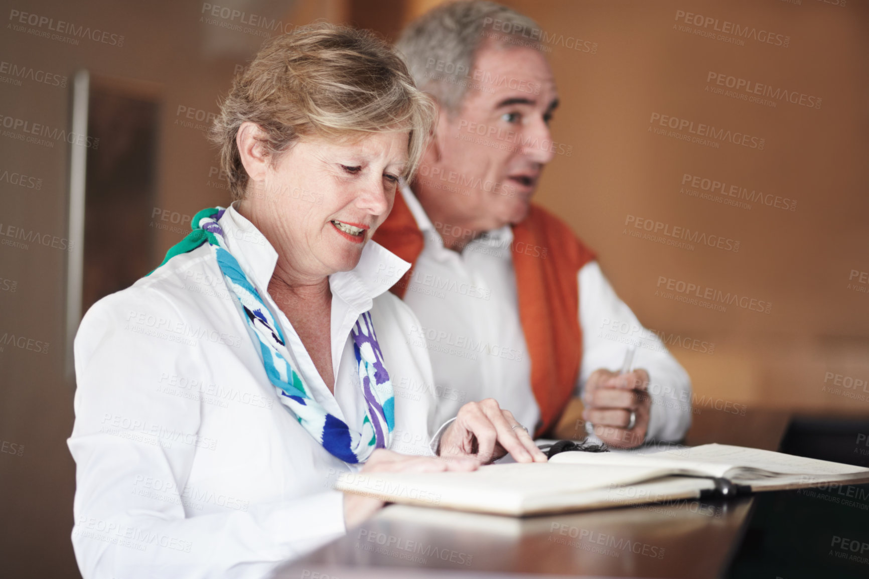 Buy stock photo Senior couple, reading and signing documents at hotel reception desk for booking, reservation or vacation. Mature man and woman filling forms, application or checking paperwork or sign in at resort