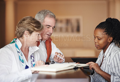 Buy stock photo A senior couple filling out forms at the hotel reception desk