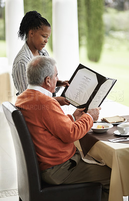 Buy stock photo A senior man being shown the specials on a menu by his waitress