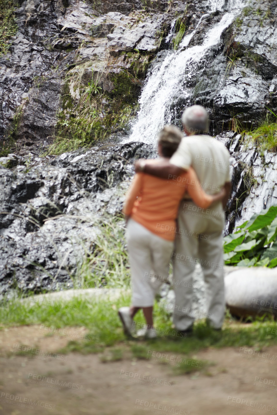 Buy stock photo Back, hug and senior couple with vacation, waterfall and nature with holiday, romance and relationship. Romantic, outdoor and elderly man with old woman, embrace and view with hike, love and relax