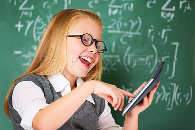 Buy stock photo Girl, calculator and happy for education, learning and problem solving or solution on chalkboard. Smart student, kid or child with glasses and excited for school, typing numbers and math in classroom