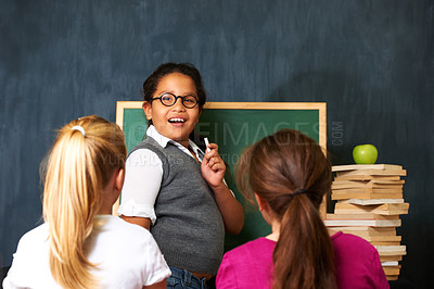 Buy stock photo Teaching, smile and portrait of kid student by board for lesson, knowledge or education with friends. Happy, glasses and girl child talking and writing with chalk for classmates in school or academy.