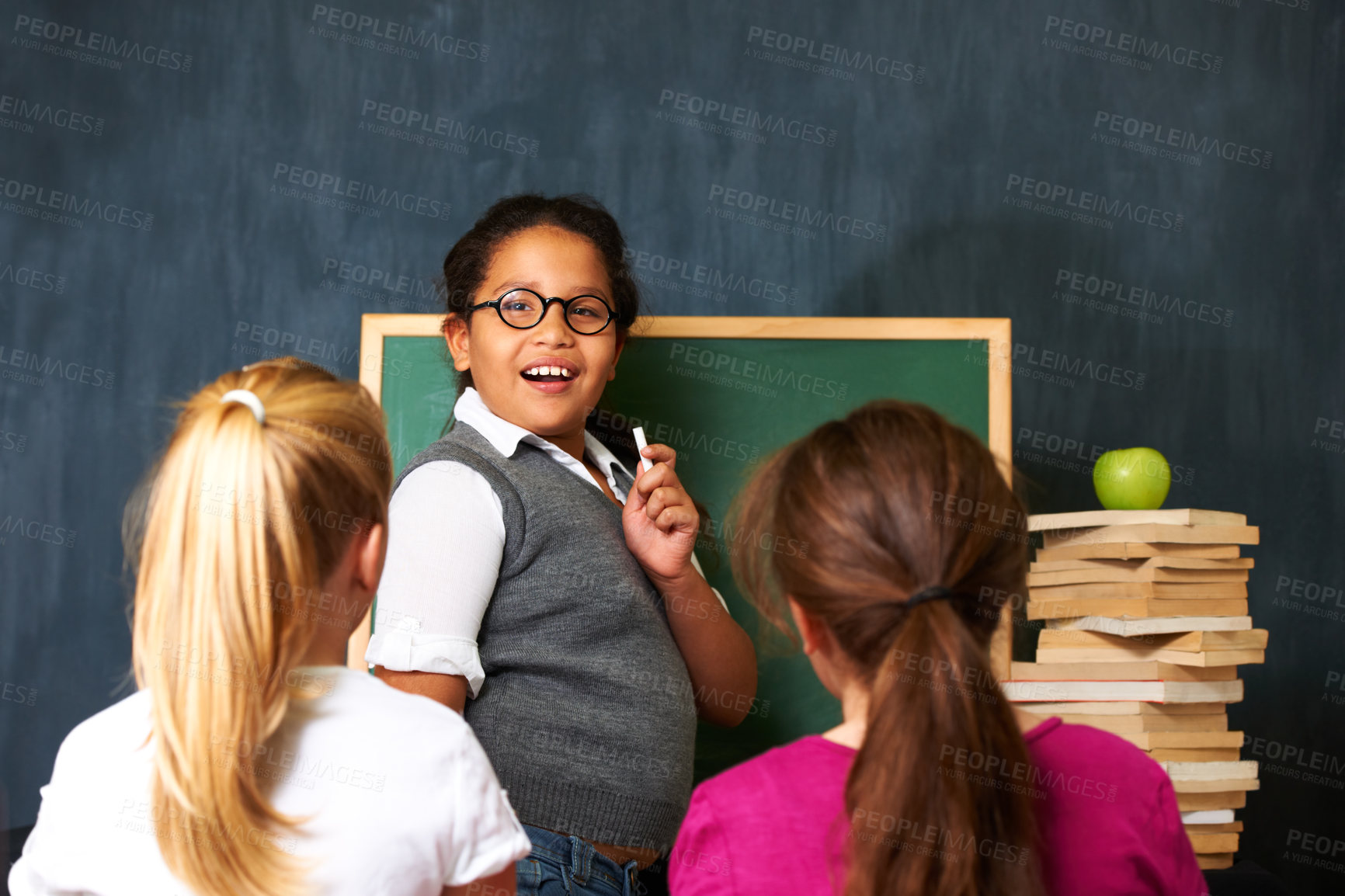Buy stock photo Teaching, smile and portrait of kid student by board for lesson, knowledge or education with friends. Happy, glasses and girl child talking and writing with chalk for classmates in school or academy.