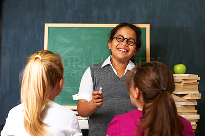 Buy stock photo Portrait of a cute girl teaching her two classmates something using the chalkboard i class