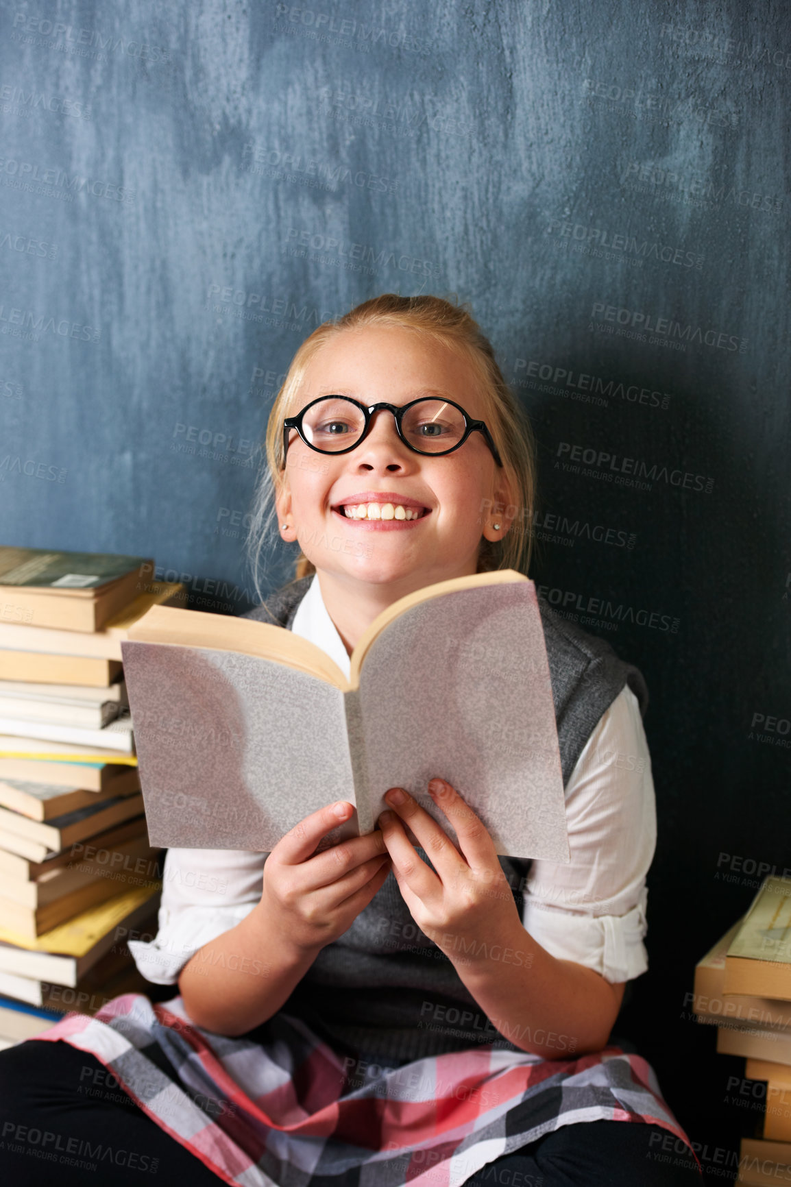 Buy stock photo Girl reading book, student and chalkboard for education, language learning and knowledge in classroom. Smart kid or child with glasses and happy for school library, fiction and literature in portrait