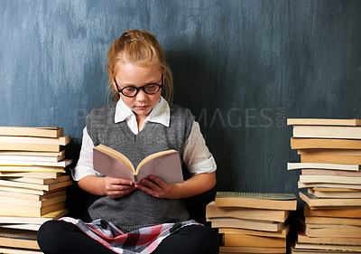Buy stock photo A cute blonde girl reading in class during break surrounded by books