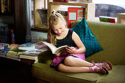 Buy stock photo Child, girl on sofa and reading book for happy learning, education and funny story with knowledge or creative mind. Kid relax on couch with literature, English story and library in home living room