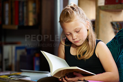 Buy stock photo Girl, child and library for reading book, education and learning of language, literature and fiction story on sofa. Kid relax in bookstore with novel for creative development, knowledge and school