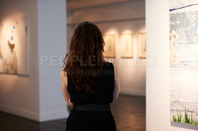 Buy stock photo Shot of a young woman looking at paintings in a gallery