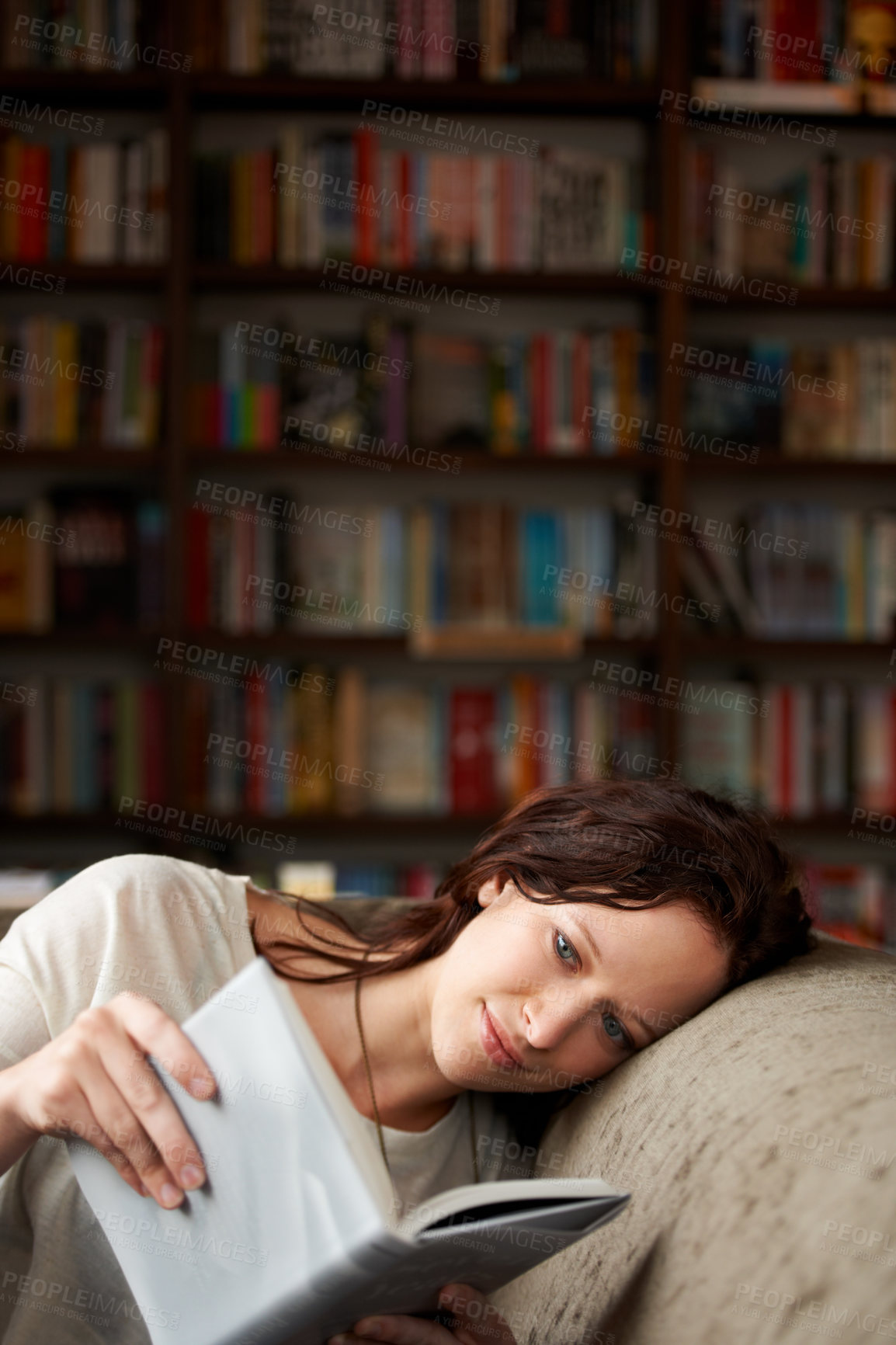 Buy stock photo An attractive young woman relaxing on a sofa with a book - copy space