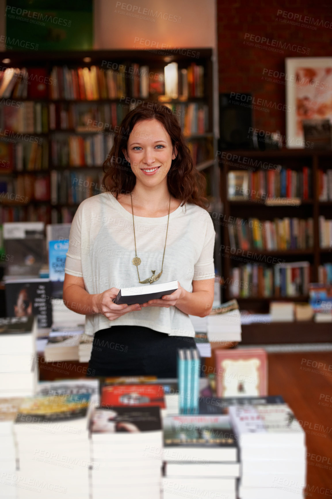 Buy stock photo Portrait of a smiling woman browsing in a bookstore