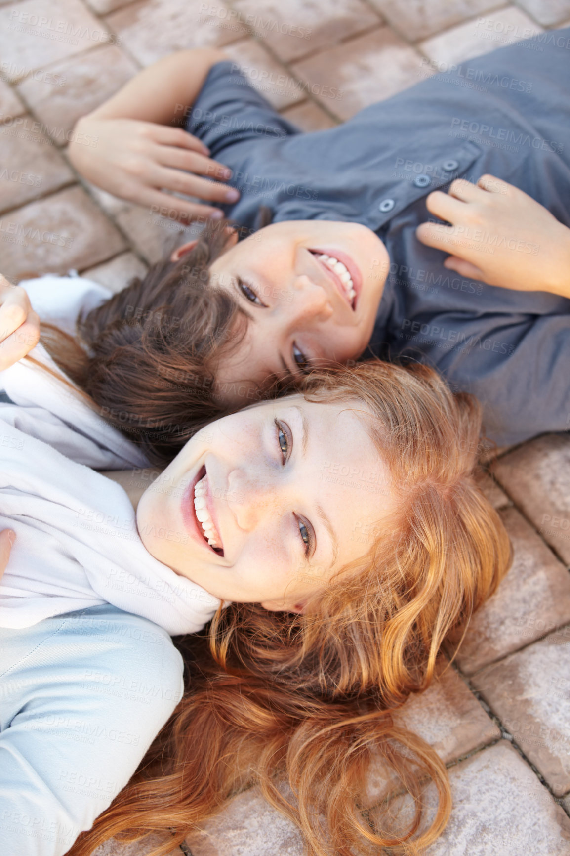 Buy stock photo Portrait of a brother and sister lying on the floor with their heads together