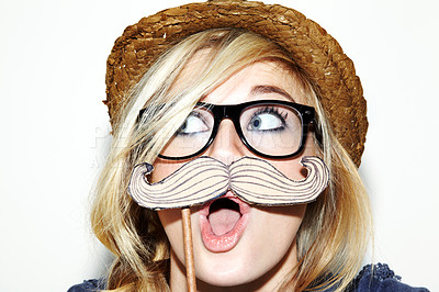 Buy stock photo Closeup of a young woman holding a moustache prop up to her face and looking surprised