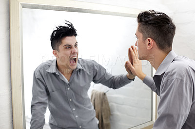 Buy stock photo Young man looking at a screaming reflection of himself in a mirror