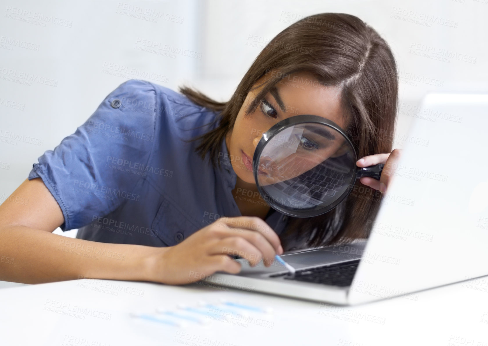 Buy stock photo Young woman using a magnifying glass while cleaning her laptop keyboard
