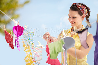 Buy stock photo Attractive young woman hanging up her washing on a line outside