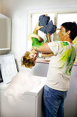 Buy stock photo Paint-covered father attempting to put his child in the washing machine