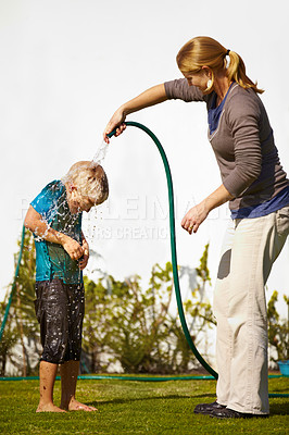 Buy stock photo Boy, woman and hose pipe with water fun, splash and playing outdoor in backyard or garden for sunshine. Kid, people or mother on grass or lawn with happiness, activity and enjoyment in summer weather