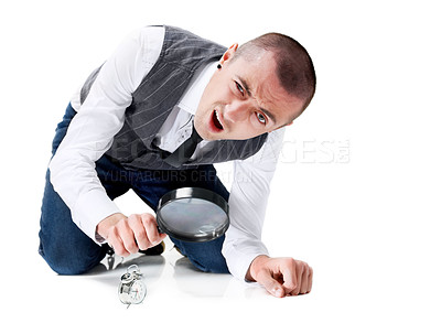 Buy stock photo A puzzled young man looking at a tiny clock through a magnifying glass